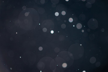 Abstract falling snow or rain bokeh texture overlay on blue background.