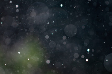 Abstract falling snow rain bokeh texture overlay on dark blue and green background.