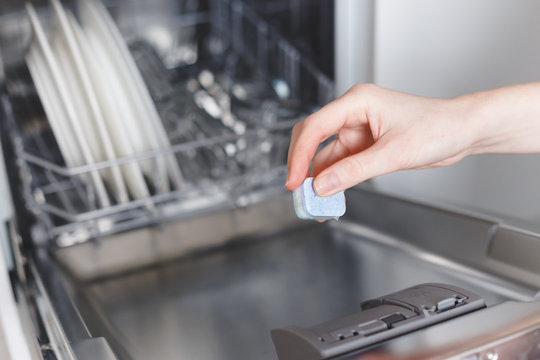 Woman Putting Tablet In Dishwasher Detergent Box