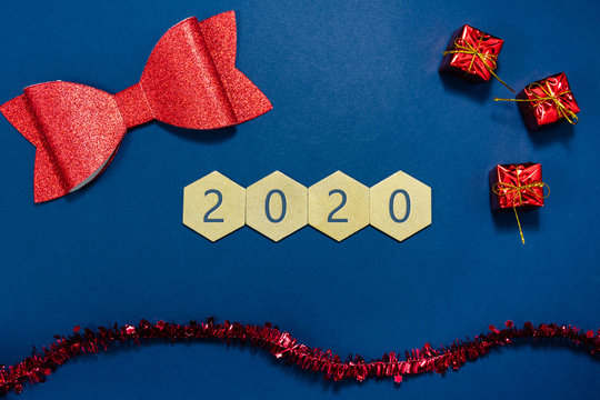 2020 written on wooden hexagons  with red christmas decorations in a conceptual image of the coming new year. Over blue background.