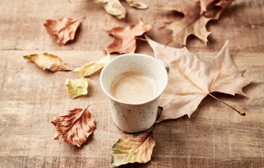 Obraz na płótnie Canvas Mug of coffee and autumn leaves. Rustic wooden background. 