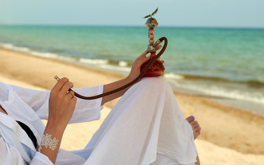 woman with a hookah on the beach smokes marijuana