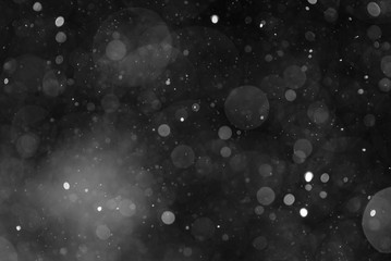 Fototapeta na wymiar Snow or rain bokeh texture on black background