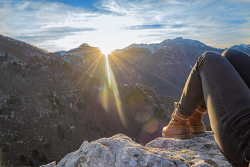 Woman resting on the edge of rocky cliff enjoying beautiful sunset in the mountains. Copy space....