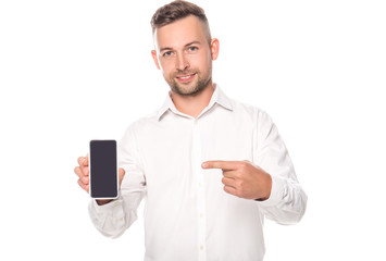 smiling businessman pointing with finger at smartphone with blank screen isolated on white