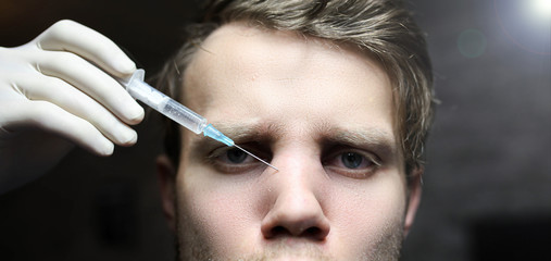 Obraz premium man is undergoing Botox treatment in a beauty clinic. Nasal bridge injection.