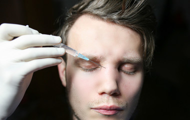Obraz premium man is undergoing Botox treatment in a beauty clinic. Nasal bridge injection.