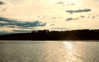 Obraz premium evening summer landscape on the river, clouds in the sky are reflected in the water, a sunny path on the water
