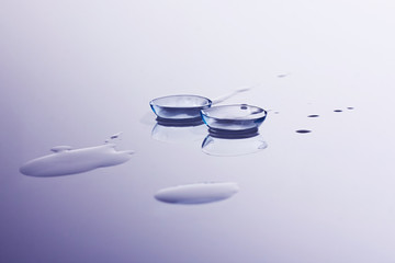 Contact lenses and water drops on light blue background. Eyewear, eyesight, eye care and health,...