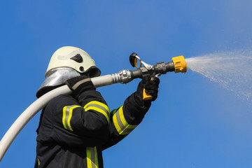 Firefighter spraying high pressure water to fire