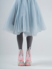 Front view woman standing in a pink rollers shoes and pastel blue skirt, cropped body on a white background