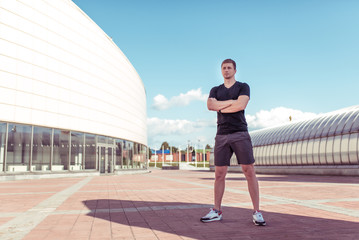Fototapeta na wymiar Male athlete, in summer in city, posing as a leader, coach teacher and mentor, morning and afternoon in the city. Sportswear. Motivation and lifestyle of youth. Free space for copy text.