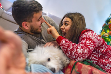 Couple making selfie with dog with reindeer horn for Christmas