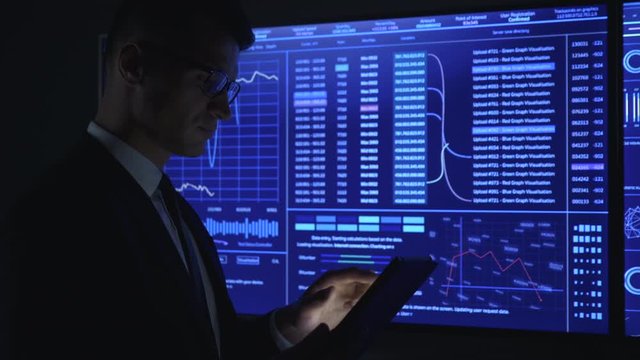 The man working with sensor tablet in the dark lab