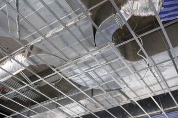 Install the air duct system above the ceiling structure inside the building.