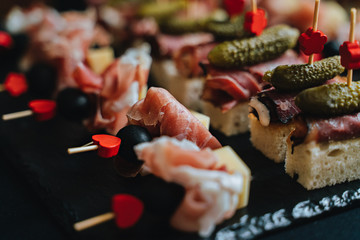Beautifully decorated catering banquet table with different food snacks and appetizers with sandwich, caviar, fresh fruits on corporate christmas birthday party event or wedding celebration