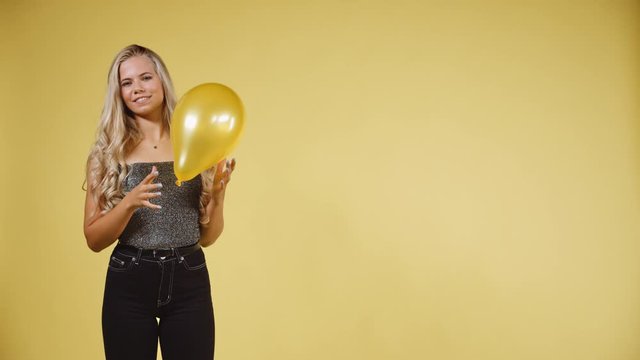 Sexy Model Throwing and Catching a Yellow Ballon against Yellow Background