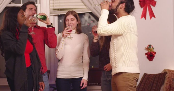 Friends cheers and clink drinks together by a Christmas tree at a party - shot on RED