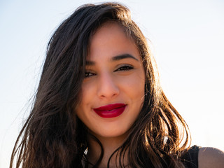 Close-up portrait of young long-haired brunette smiling at the beach