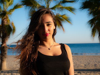 Close-up portrait of young long-haired brunette smiling at the beach