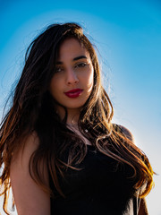 Fototapeta premium Close-up portrait of young long-haired brunette smiling at the beach