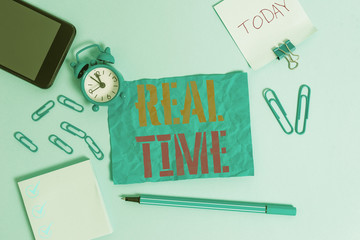 Word writing text Real Time. Business photo showcasing the actual time during which a processes or events occurs Alarm clock clips notepad smartphone rubber band marker colored background