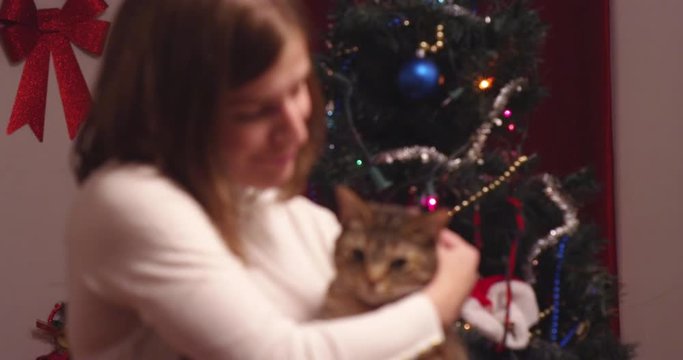 Young woman lifts up and cuddles a cat with blinking lights in background - slow motion - shot on RED