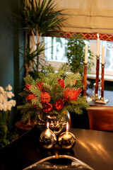 the Modern Lifestyle Contemporary Vase with Red Flowers and Round and Golden Candlesticks on Wooden Table with Window Background