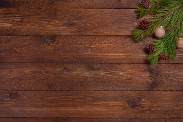 Christmas or New Year decoration background. Spruce branches with cones and balls, on dark wooden  background. Flat lay, top view, copy space.