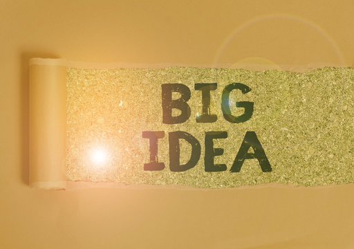 Text sign showing Big Idea. Business photo text Having great creative innovation solution or way of thinking Cardboard which is torn in the middle placed above a wooden classic table
