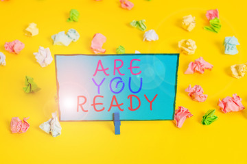 Text sign showing Are You Ready. Business photo showcasing Alertness Preparedness Urgency Game Start Hurry Wide awake Colored crumpled papers empty reminder white floor background clothespin