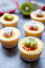 Mini New York Cheesecakes Recipe with Kiwi fruit and Dragon fruit on  wooden board.