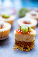 Mini New York Cheesecakes Recipe with Kiwi fruit and Dragon fruit on  wooden board.
