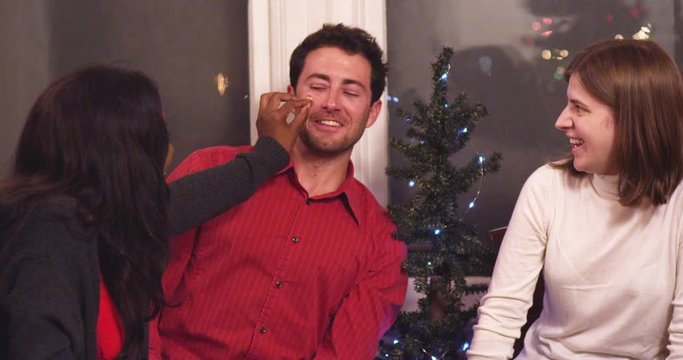 Young woman places a star sticker on her friend's cheek at a holiday party - slow motion - shot on RED