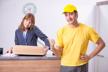 Young male courier delivering box to hotel's reception