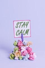 Handwriting text Stay Calm. Conceptual photo Maintain in a state of motion smoothly even under pressure Reminder pile colored crumpled paper clothespin reminder blue background