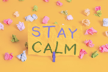 Handwriting text writing Stay Calm. Conceptual photo Maintain in a state of motion smoothly even under pressure Colored crumpled papers empty reminder white floor background clothespin