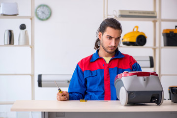 Young male contractor repairing vacuum cleaner at workshop