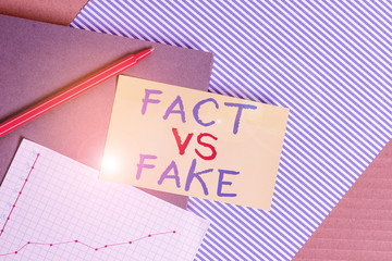 Conceptual hand writing showing Fact Vs Fake. Concept meaning Rivalry or products or information originaly made or imitation Striped paperboard cardboard office study supplies chart