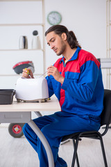 Young male contractor repairing toaster at workshop