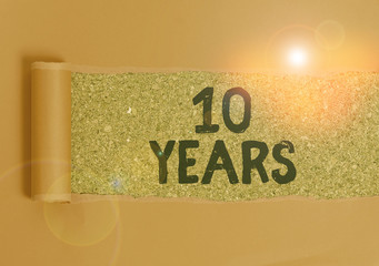 Text sign showing 10 Years. Business photo text Remembering or honoring special day for being 10 years in existence Cardboard which is torn in the middle placed above a wooden classic table