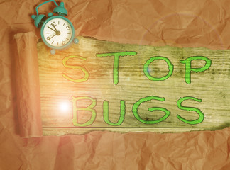 Writing note showing Stop Bugs. Business concept for Get rid an insect or similar small creature that sucks blood Alarm clock and torn cardboard on a wooden classic table backdrop