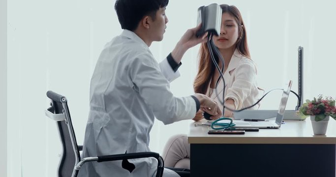 Close up scene video of handsome Asian male doctor using sphygmomanometer to checking beautiful patient's blood pressure in health check day in hospital