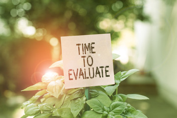 Text sign showing Time To Evaluate. Business photo showcasing moment rate used before products or service Give feedback Plain empty paper attached to a stick and placed in the green leafy plants