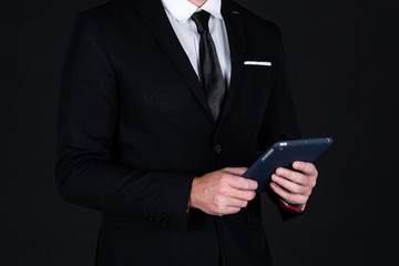 Confident businessman in black suit using technology on hand