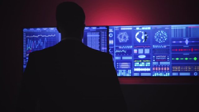The man walking to the blue screen in a dark space