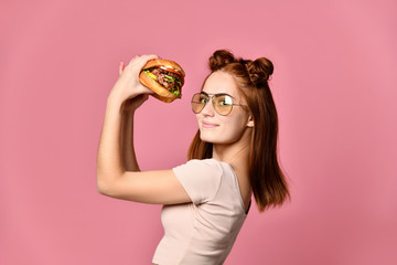 Woman eat burger sandwich with hungry mouth on pink background.
