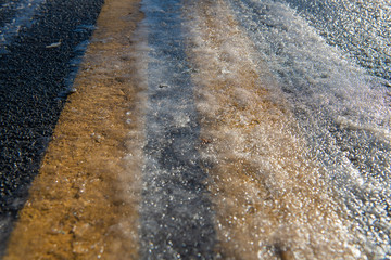 Asphalt road with double yellow lines covered with ice