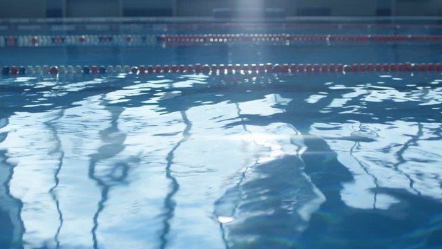 Blue waves in the pool shimmer with bright light from the incident sunlight. Slow mo, slo mo, slow motion, high speed camera