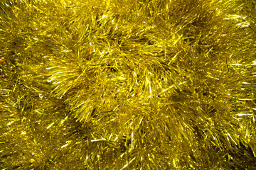 Christmas background. Christmas yellow texture with golden abstract christmas decorations. Concept background for New Year and Christmas holidays with sparkles and tinsel. Luminous pattern copyspace